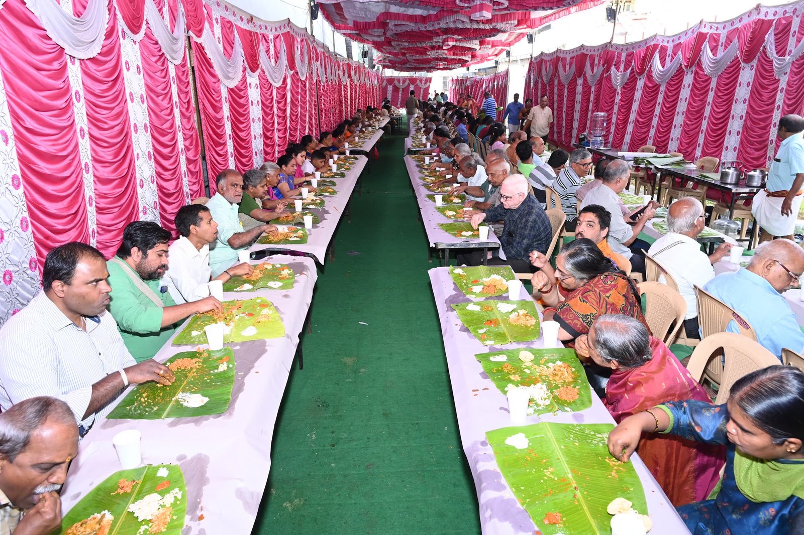 Devotees seated in rows for the prasadam, served on banana leaves